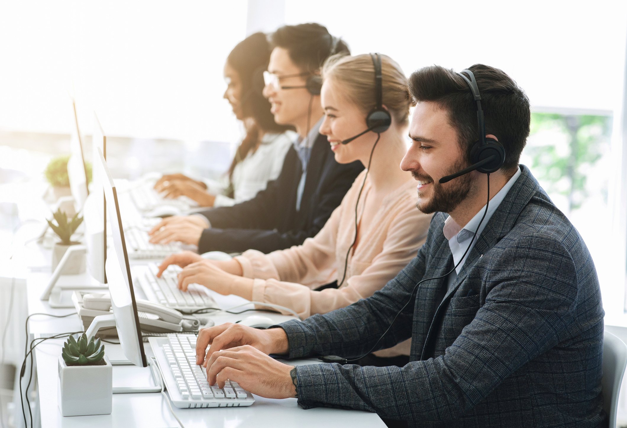 Telemarketing or hotline operators working with computers at light office